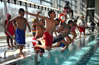 Kids jumping a pool as a lifeguard looks on