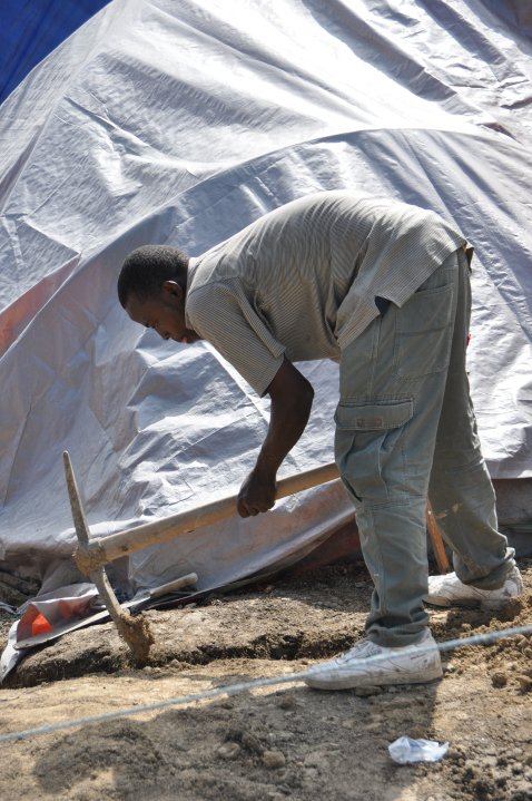 A local Haitian man digs a trench around his temporary housing so it won’t flood - photo by Cora Maglaya