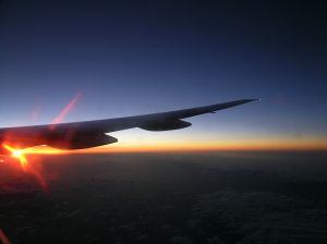 Sun rising under wing of airplane
