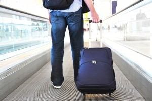 airport traveler with suitcase on walkway, credit bigstock